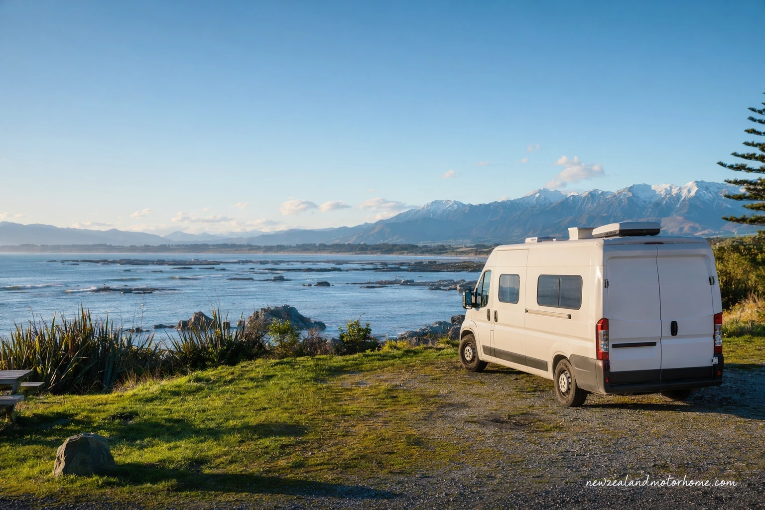 Campervan parked near the Kaikōura coast with mountains and the Pacific Ocean in view