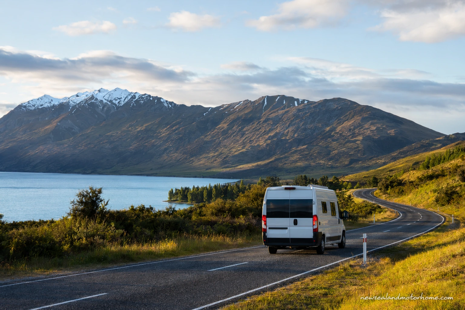 Campervan parked beside a wide Canterbury high-country road with mountains in the distance