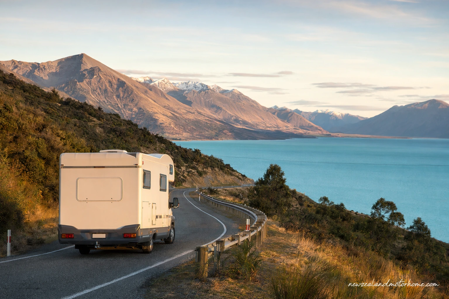 Campervan parked beside a quiet New Zealand lake with mountains in the background