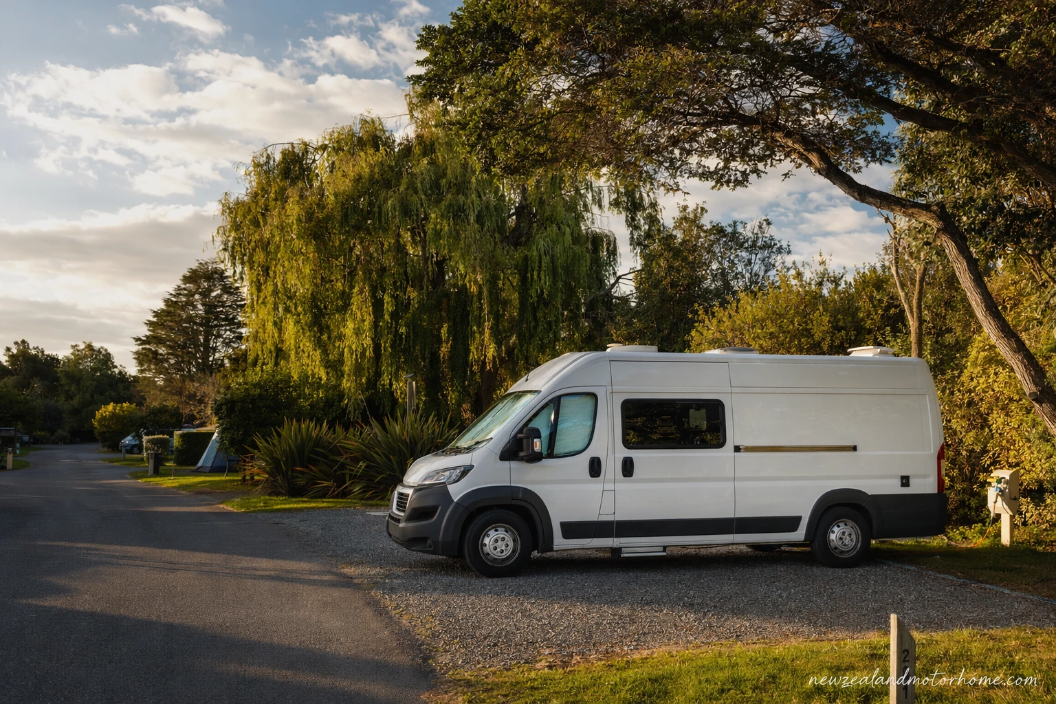 Campervan parked at a Christchurch holiday park site with trees and Canterbury sky
