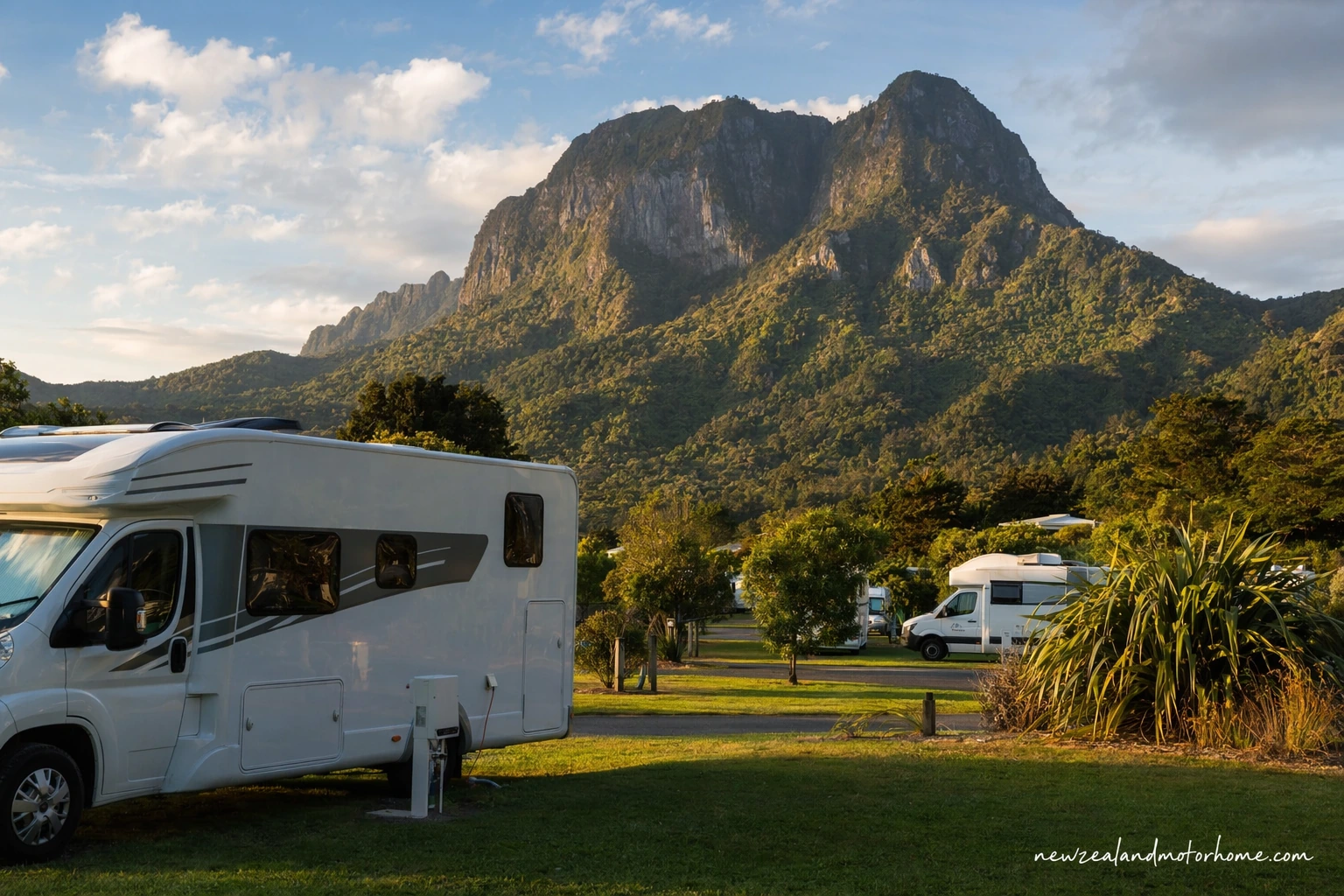Campervan parked at a coastal holiday park on the Coromandel Peninsula with beach and pohutukawa nearby