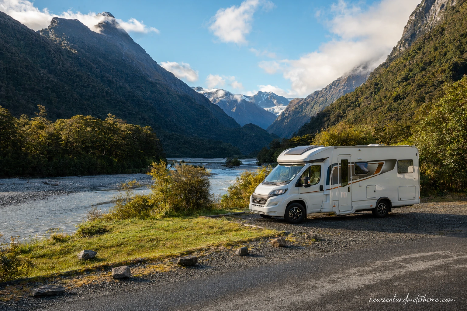 Campervan parked near Haast with West Coast rainforest, river flats and misty mountains in the background