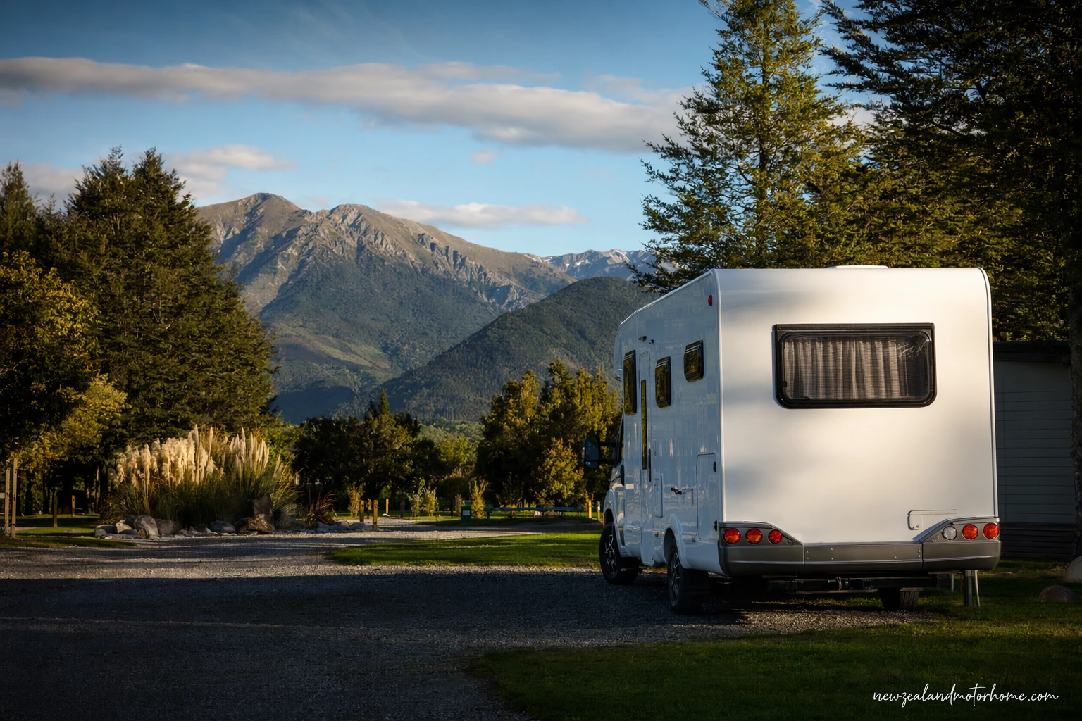 Campervan parked at a Hanmer Springs holiday park with alpine hills and trees in the background