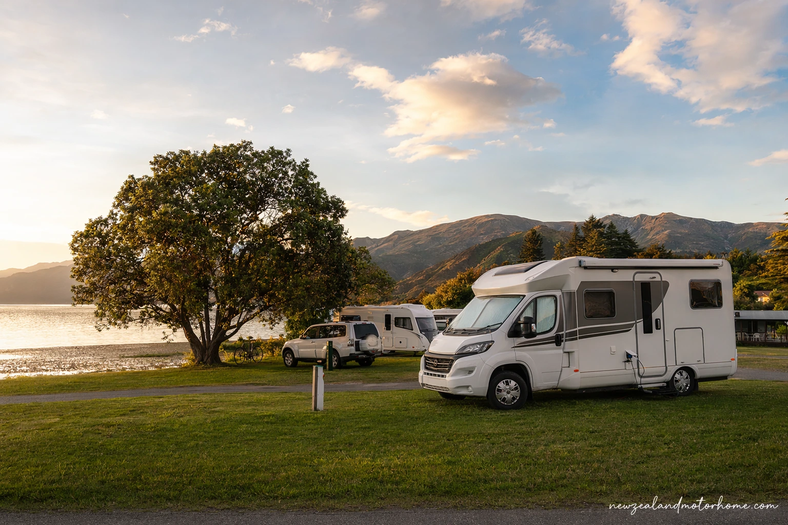Campervan parked at a Nelson Tasman holiday park near the coast with hills behind