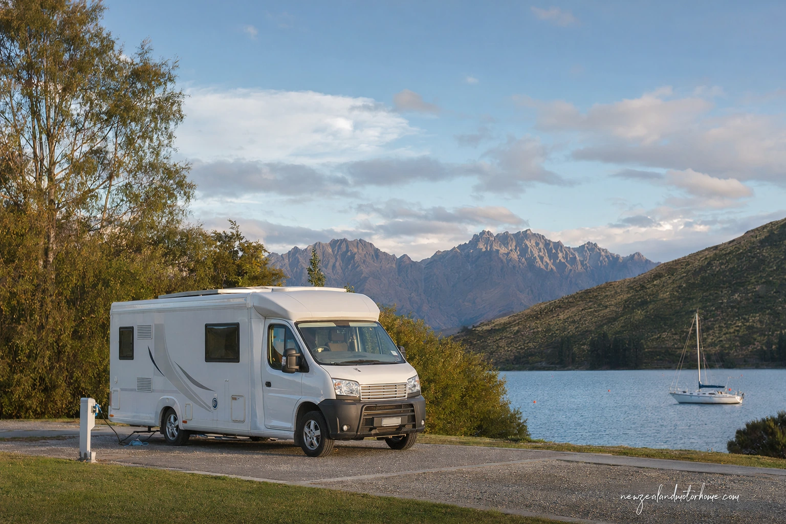 Campervan parked at a holiday park near Queenstown with mountains and Lake Wakatipu nearby
