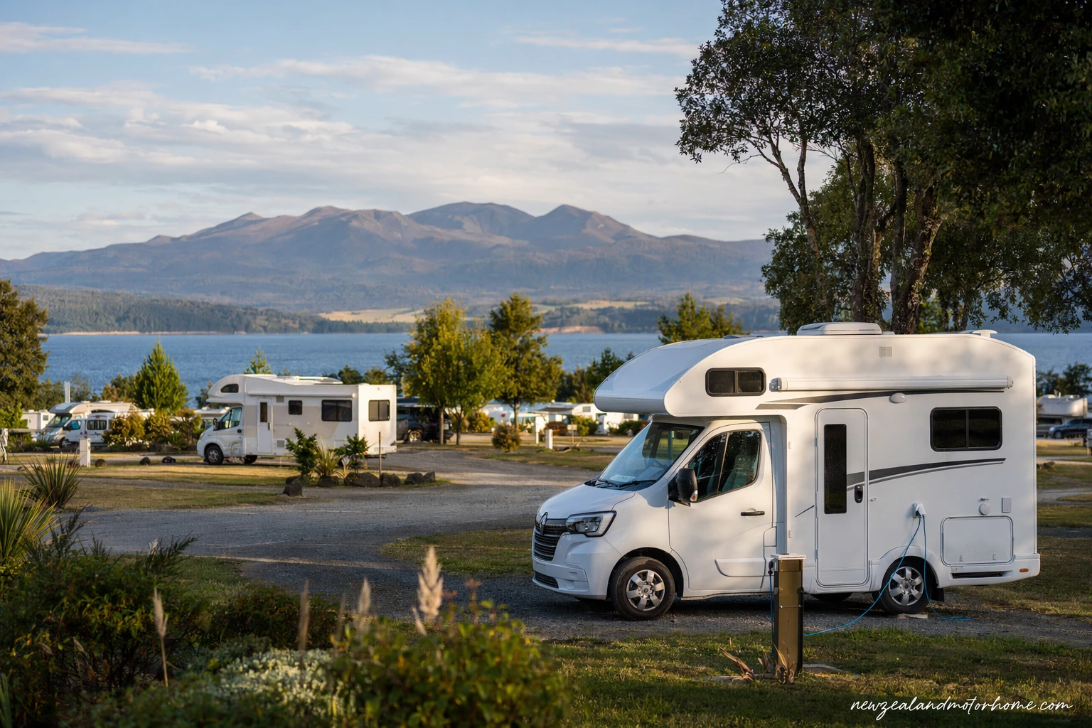 Campervan parked at a Taupo holiday park near the lake with mountains in the distance
