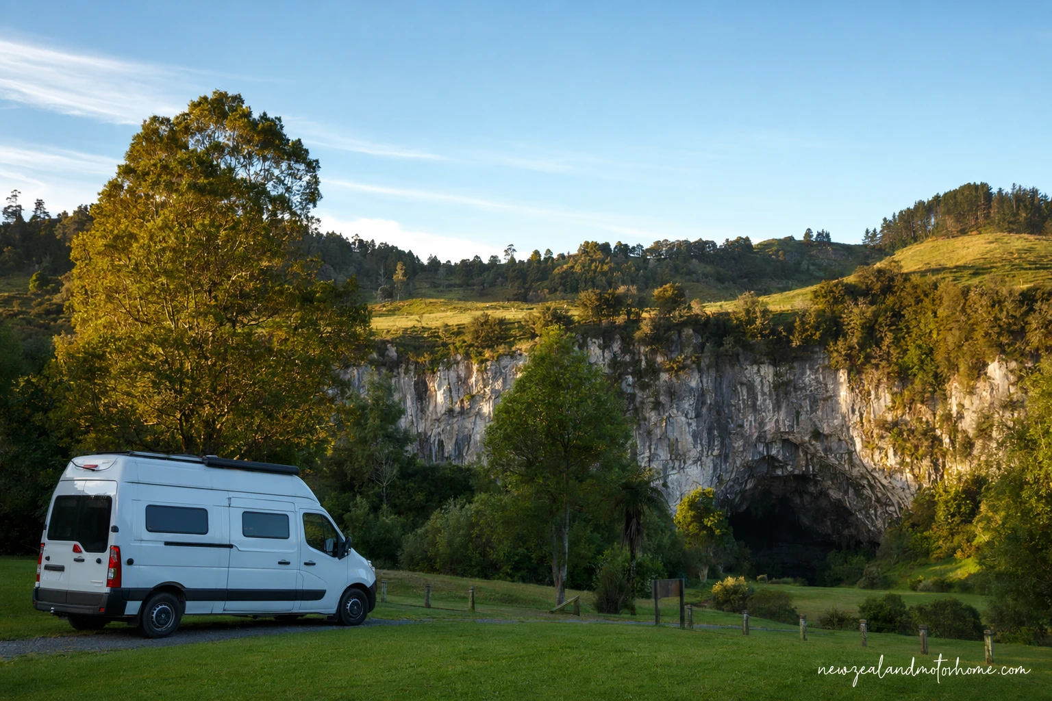 Campervan parked near Waitomo holiday park surroundings with green limestone hills and cave country scenery